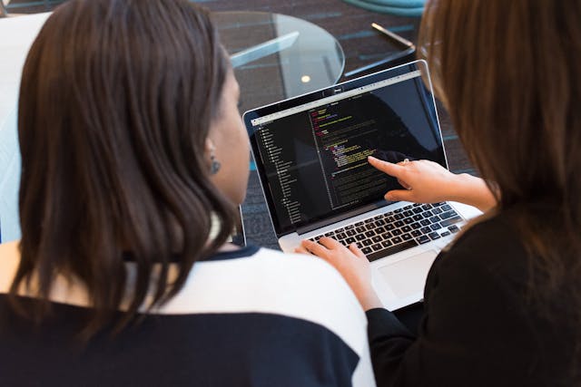 Two women looking at the code on a laptop